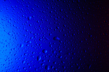 Drops of water on glass in blue neon light. Rain on the glass against the background. Abstract photo for background. light. Rain on the glass