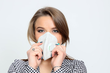 Beautiful young brunette girl is wearing a protective medical mask due to Corona virus. Health care concept, protection against Covid 19.