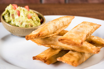 Latin-American appetizers called Tequenos made of fried wonton filled with cheese and is served with guacamole