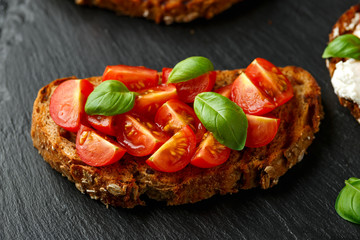 Bruschetta with cherry tomato and basil on rustic stone board