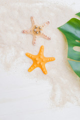 Flat lay composition with starfish, sand and palm leaves on a light background