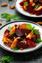 Vegan Plum, beet salad with pecan nuts, mint and herbs on rustic black table