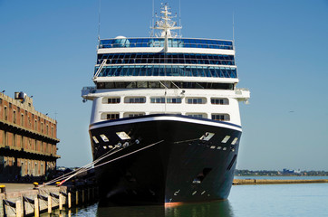 Luxury classic cruiseship or cruise ship liner in port with pier and reflection on water on summer...