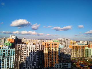 
A panorama of the city from a height with bright colorful houses and a distant horizon with a big city and a blue sky with clouds