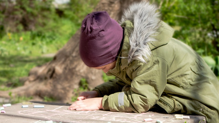 Fototapeta premium Boy draw with colored chalk on concrete in the park on a warm spring day