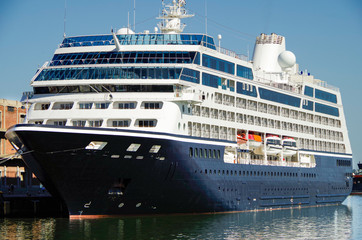 Luxury classic cruiseship or cruise ship liner in port with pier and reflection on water on summer...