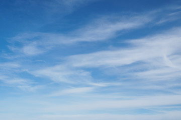 Cirrus clouds on blue sunny spring sky, nature background without focus.
