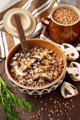 Buckwheat porridge with mushrooms in ceramic pot on table
