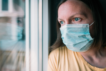 Woman in self-isolation during virus outbreak looking through window