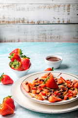 Pancakes with fresh strawberry on a blue wooden background