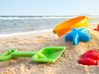Colorful plastic toys on sand. Creative activity in summer season.