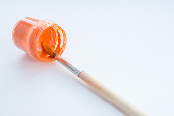 plastic jar with orange paint and brush