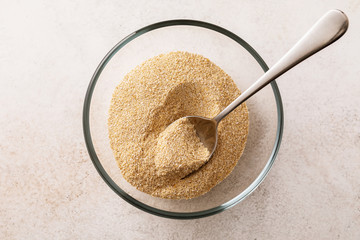 Oat bran in a transparent plate with a spoon on the table, top view