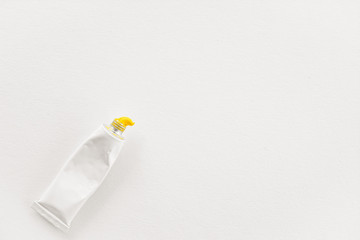 a tube of paint on paper. the view from the top. yellow paint squeezed out of a tube