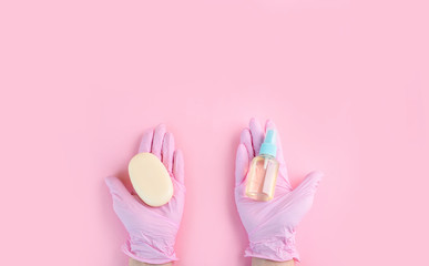 Hands in medical gloves lie on a pink background.