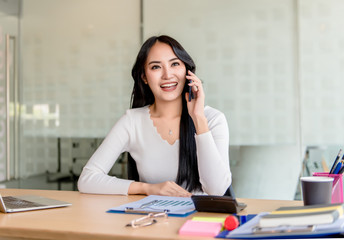 Fototapeta premium Young, happy, cheerful, bright, cute, beautiful business women with a smile on the phone, sitting in the house, in the office, using a laptop computer, work at home concept.