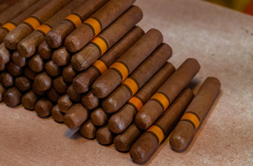 Cuban cigars close up on wooden table. Side view of a cigars bunch. Handmade cigars in the shop.