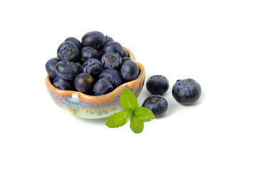 Bowl of fresh blueberries isolated on white background. Healthy organic seasonal fruit background. Organic food blueberries and mint leaf for healthy lifestyle.