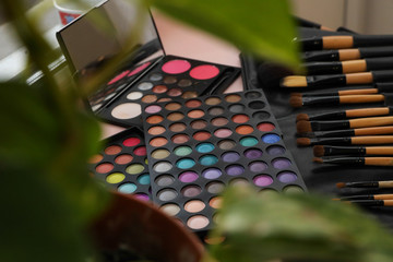 A palette of shadows and brushes on the table next to the flowers