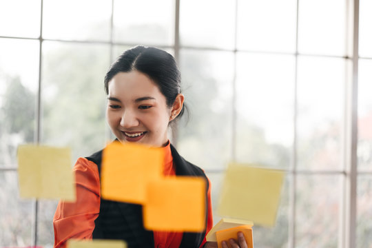 Business Asian Woman Use Post It Stick On Glass Board With Window Light.