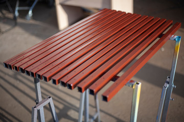 Painted metal profile. Steel in brown paint. Work in the workshop. Sliced steel square pipes. Creating a design. Preparatory actions. Natural light. Saturated colors. Neatly done.
