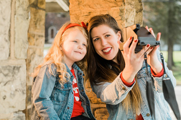 Mother and daughter taking selfie with instant camera