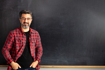 Adult man teacher posing on blackboard.