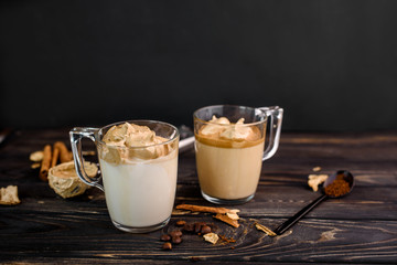 Delicious and fragrant dalgona coffee in glass cups, cinnamon sticks, dried mushrooms, a spoon of instant coffee, sugar.