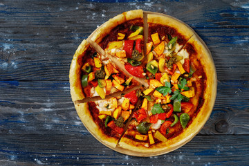 Top view of delicious vegan pizza cut into peaces on blue background
