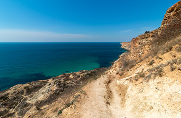 Fototapeta na wymiar Mountain path on the rocky shore of the turquoise sea. Cape Fiolent, Sevastopol