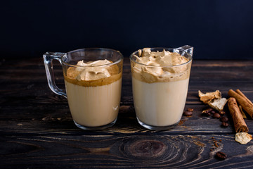 Delicious and fragrant dalgona coffee in glass cups, cinnamon sticks, dried mushrooms, a spoon of instant coffee, sugar.