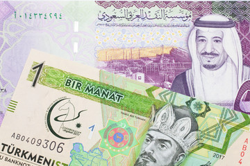 A green one manat note from Turkmenistan close up in macro with a five Saudi riyal bank note from Saudi Arabia's central bank