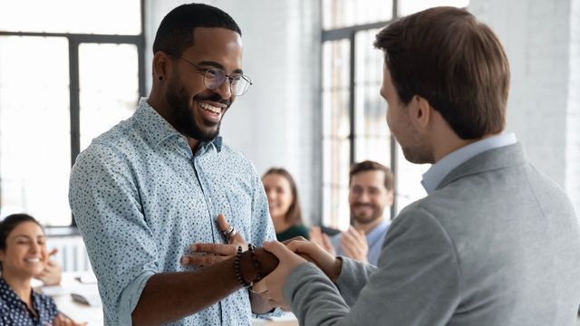 Caucasian businessman handshake African American male employee congratulate with work achievement or success, boss shake hand of biracial worker greeting with job promotion at office meeting