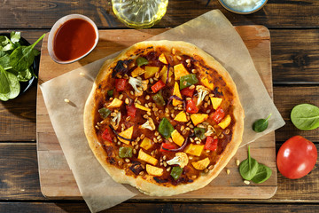 Top view of vegan home-made pizza with vegetables, pesto and pine nuts