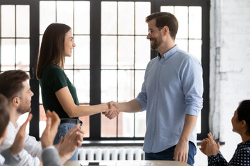 Happy businessman shake hand of excited female employee greeting with work promotion, colleagues...
