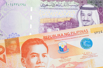 An orange twenty piso note from the Philippines close up in macro with a five riyal note from Saudi Arabia