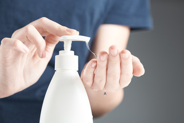 Female hands using hand sanitizer gel pump dispenser. A stream of clear gel drips down from hand.