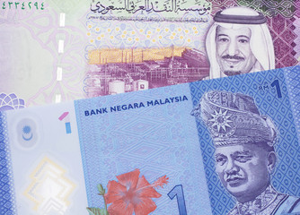 A blue, one ringgit Malaysian note close up in macro with a five riyal note from the Saudi Arabia