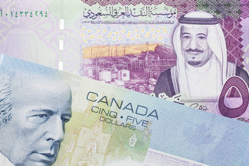 A close up macro shot of a blue five Canadian dollar bill with a five Saudi riyal note
