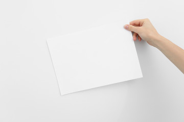 Woman hand holding the paper on white background. place for text. blank piece of inscription paper