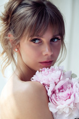 Beautiful girl holding peonies, attractive woman with big bouquet, female smells flowers, studio with sunlight.