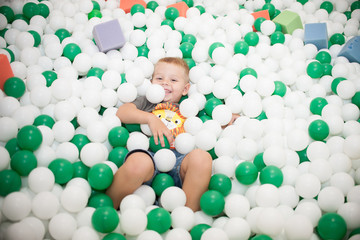 Fototapeta na wymiar the child lies in colorful balloons and smiles children's Playground