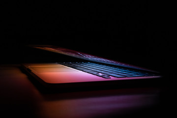 laptop half closed from the side in the dark
