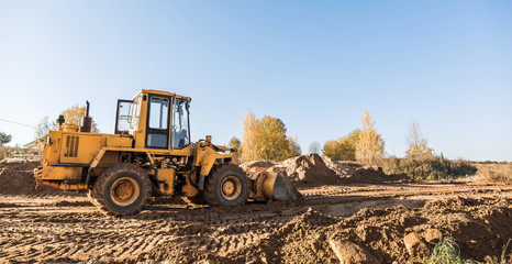 large yellow wheel loader aligns a piece of land for a new building. Preparation of the land for...