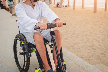 Obraz premium Disabled man in a wheelchair with electric scooter on the beach
