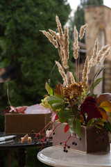 box with business cards on a black round table, a box with hydrangea, celosia flowers, elderberry branches and reeds on a white round table