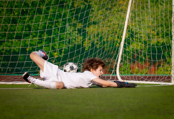 junior soccer goalkeeper. Disappointed boy in white goalie sportswear. Goalkeeper missed a goal during friendly match.