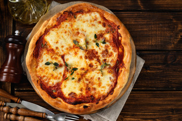 Top view of delicious home-made pizza margherita on dark wooden background
