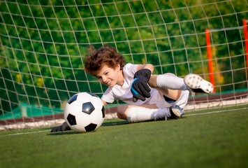 Summer soccer tournament for young kids. football club. emotions and joy of the game. Young goalie. Kids - soccer champion. Boy goalkeeper in football sportswear on stadium with ball. Sport concept.