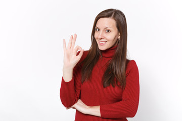 Smiling young brunette woman girl in casual red clothes posing isolated on white wall background studio portrait. People sincere emotions lifestyle concept. Mock up copy space. Showing OK gesture.